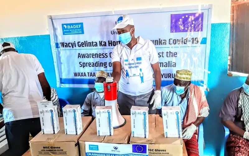 BADEF staff with protective equipment beside a COVID-19 awareness banner in Merka